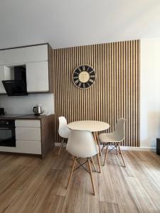 a kitchen with a table and chairs and a clock on a wall at Apartament Rejtana in Leszno +5 photos