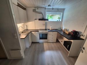 a small kitchen with white cabinets and a sink at Cozy Home in Stokmarknes