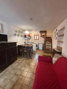 a living room with a red couch and a kitchen at Vecchio Mulino- Via Paier in Entracque