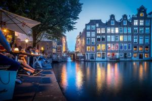 a view of a canal at night with people sitting under an umbrella at Hotel Bet van Beeren in Amsterdam