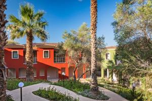 an orange building with palm trees in front of it at Suites Del Borgo in Olbia