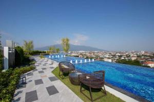 a pool with chairs and a view of a city at The Astra Sky River Condo Chiang Mai in Chiang Mai