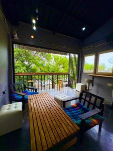a screened in porch with a wooden table and chairs at Crew Bangkok Hostel in Bangkok