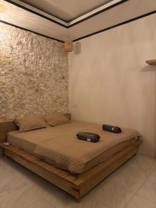 a bed in a room with a stone wall at Simagirau Homestay in Simpatdegat