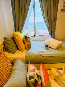 a room with two beds with pillows and a window at Bienvenida Condotel in Dumaguete +25 photos