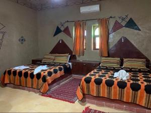 two beds sitting in a room with at Riad Kasbah Le Touareg in Merzouga
