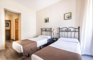 two beds in a room with white walls at Hostal El Pilar in Madrid