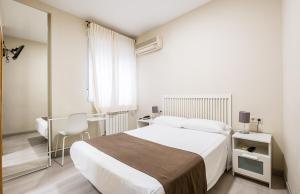 a bedroom with a bed and a desk with a chair at Hostal El Pilar in Madrid +112 photos