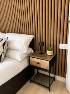 a bed with a table with a lamp on top of it at Wellingborough Luxury Staycation 3 Bed 2 Bath in Wellingborough