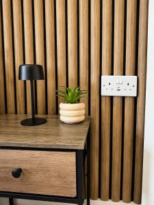 a desk with a lamp and a plant on it at Wellingborough Luxury Staycation 3 Bed 2 Bath in Wellingborough
