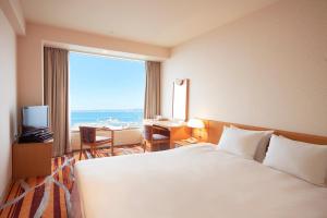 a hotel room with a bed and a desk and a window at Kushiro Prince Hotel in Kushiro
