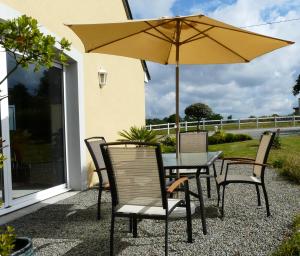 a table and chairs with an umbrella on a patio at Chambre d'hôtes Le Pot au Lait in Villaines-la-Juhel