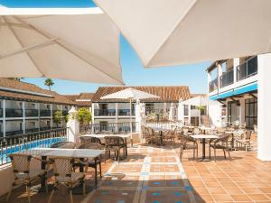 an outdoor patio with tables and chairs and umbrellas at Ona Diana Park in Estepona