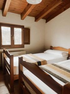 a bedroom with three beds in a room with wooden ceilings at Alberg rural torre del baró in Sant Llorenç de Morunys
