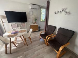 a living room with a table and chairs and a television at Mon Paradis en Provence B29 in Gréoux-les-Bains