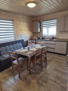 a kitchen and dining room with a table and a couch at Domki Letniskowe U Żuni in Chłopy
