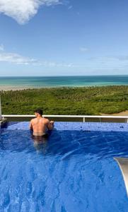Ein Mann in einem Swimmingpool mit Blick auf das Meer in der Unterkunft Silverton Flats Paiva Experience in Recife + 39 Fotos