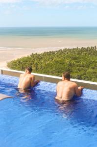 zwei Männer sitzen in einem Schwimmbecken im Meer in der Unterkunft Silverton Flats Paiva Experience in Recife