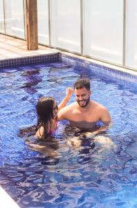Ein Mann und eine Frau in einem Schwimmbecken in der Unterkunft Silverton Flats Paiva Experience in Recife