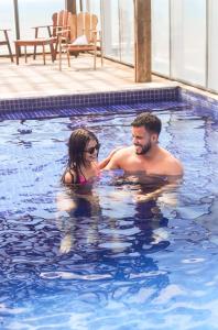 Ein Mann und eine Frau in einem Schwimmbecken in der Unterkunft Silverton Flats Paiva Experience in Recife