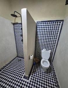 a bathroom with a toilet and a black and white checkered floor at Riad Kasbah Le Touareg in Merzouga +37 photos