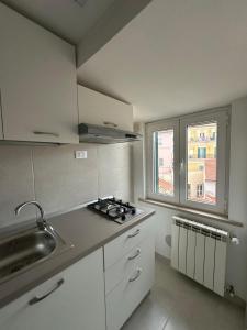 a kitchen with white cabinets and a sink and a window at Cozy Apartment in Chieti Centro in Chieti