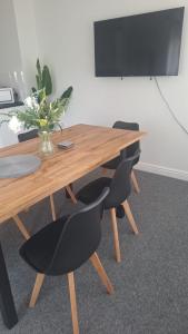 a wooden table with two chairs and a vase of flowers at Spacious airy modern private detached house in Beeston