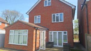 a red brick house with white windows and doors at Spacious airy modern private detached house in Beeston