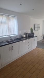 a kitchen with white cabinets and a sink at Spacious airy modern private detached house in Beeston