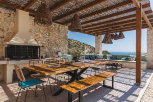 an outdoor patio with a wooden table and chairs at Apaggio Luxury Villa - Private Pool & Stunning Sea Views, by ZanteWize in Agios Nikolaos