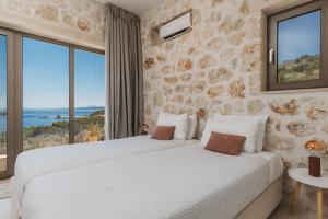 a bedroom with two beds and large windows at Apaggio Luxury Villa - Private Pool & Stunning Sea Views, by ZanteWize in Agios Nikolaos