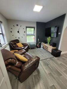 a living room with a couch and a clock on the wall at Rose Cottage Clonmel in Clonmel