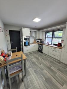 a kitchen with white cabinets and a wooden table and a dining room at Rose Cottage Clonmel in Clonmel