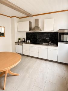 a kitchen with white cabinets and a wooden table at Workers House in Bockenem