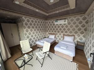 a room with two beds and a table and chairs at Neem camp in Nizwa