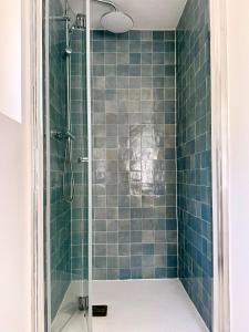 a bathroom with a shower with blue tiles at Grand T2 neuf Chartrons in Bordeaux