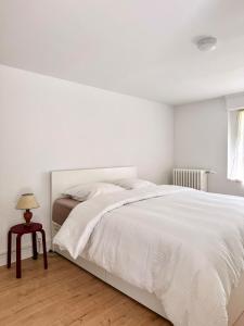 a white bedroom with a large bed and a table at Grand T2 neuf Chartrons in Bordeaux