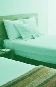 a bed with white sheets and pillows next to a table at Tharusha Hotel in Udawalawe