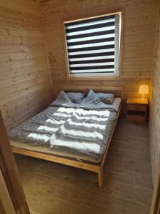 a bed in a wooden room with a window at Domki Letniskowe U Żuni in Chłopy