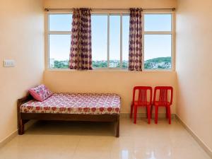 a room with two red chairs and a bed with a window at Hotel Shepherds in Bīdar