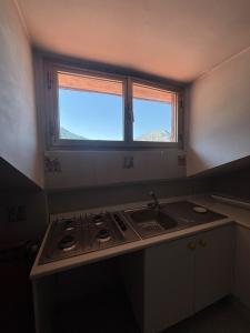 a kitchen with a stove and a sink and a window at La Mansarda del Vecchio Mulino in Entracque