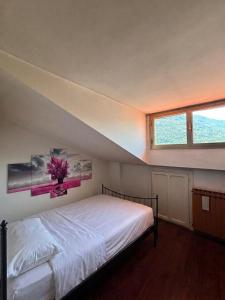 a bedroom with a white bed with a window at La Mansarda del Vecchio Mulino in Entracque