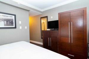 a bedroom with a large wooden cabinet and a television at Sandman Hotel & Suites Vancouver Airport in Richmond