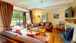 a living room with a leather couch and a table at Kinloch Lodge in Drumnadrochit
