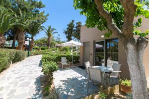 a patio with a table and chairs under a tree at Eleni Village & Suites in Amoudara Herakliou
