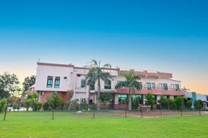 a building with palm trees in front of a field at Hotel Dhola Maru in Kota