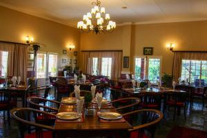 a restaurant with wooden tables and chairs and a chandelier at Platrand Lodge in Ladysmith