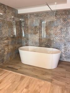 a white bath tub in a bathroom with tiles at Prenoćište Nikolić in Negotin +11 photos