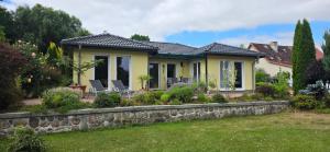 a yellow house with a stone retaining wall at Lavendelhaus am Müritzsee - direkt am Wasser in Buchholz
