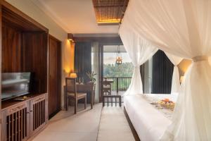 a bedroom with a bed and a television and a balcony at The Compass Rose Valley in Ubud